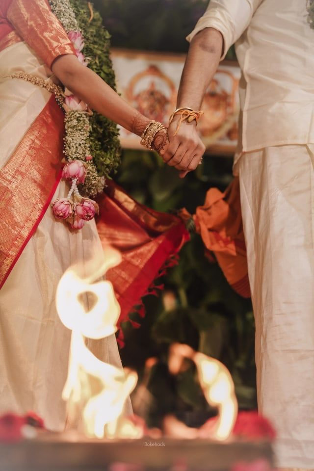 Bride in embroidered red lehenga and groom holding hands